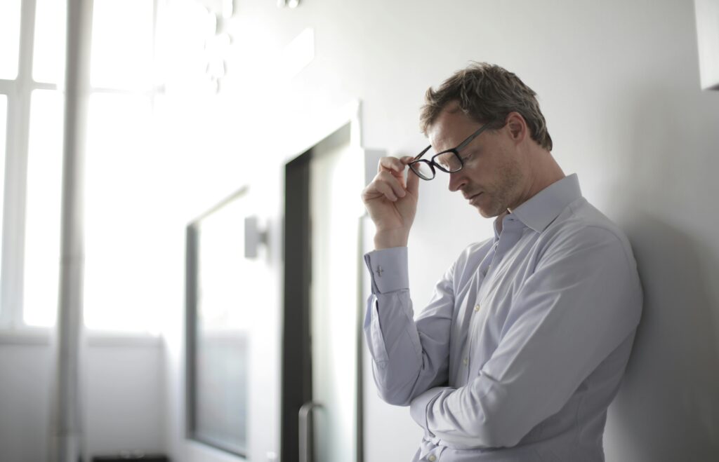Ein Mann lehnt nachdenklich an einer Wand – Effizientes Training und Ernährung ab 40 helfen, Stress zu bewältigen und gesund zu bleiben.
