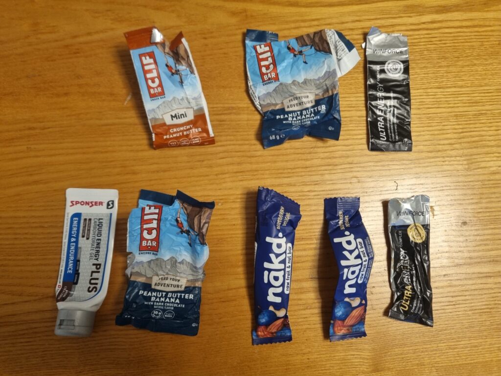 Leere Energie- und Proteinriegel-Verpackungen nach einem Ultra-Ausdauertraining – Ernährung im Fokus zyklusbasierten Trainings und Fettoxidation bei Frauen.