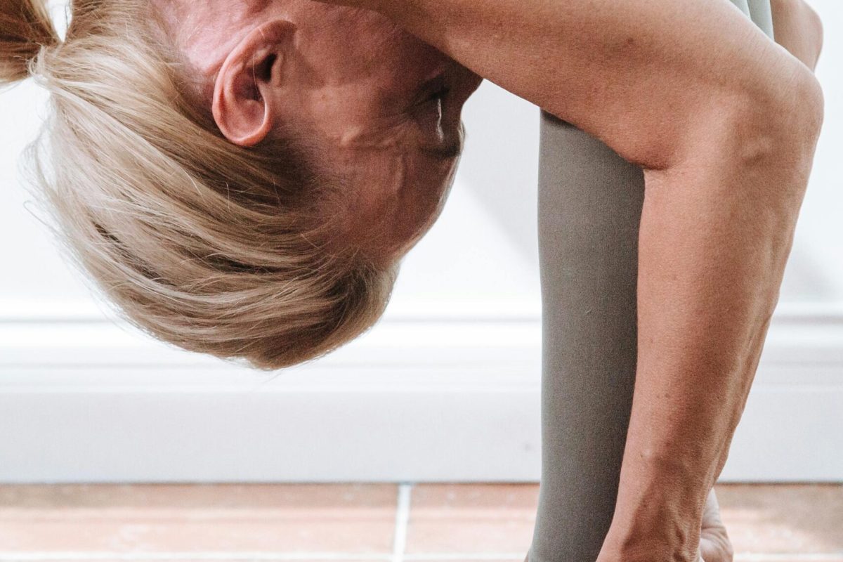 Vorwärtsbeuge-Dehnübung: Flexibilität und den Alterungsprozess ab 40 kontrollieren. Frau bei einer Vorwärtsbeuge-Dehnübung, um den Alterungsprozess ab 40 zu kontrollieren und Flexibilität sowie Beweglichkeit zu fördern.